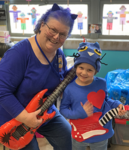 student and teacher hold blow up guitars