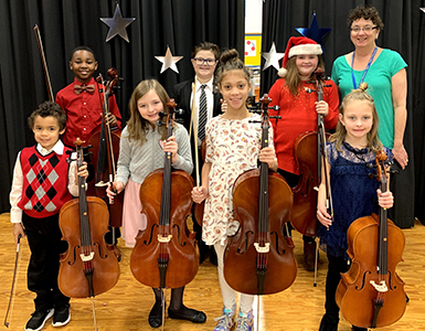 students dressed for christmas holding stringed instruments
