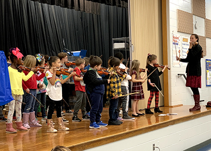 students standing on stage playing stringed instruments