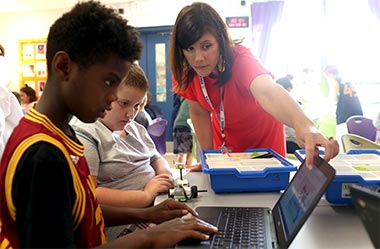 Photo of a Teacher helping a student using a laptop