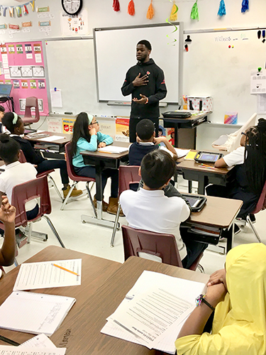 u of l basketbal player talks to students in a classroom